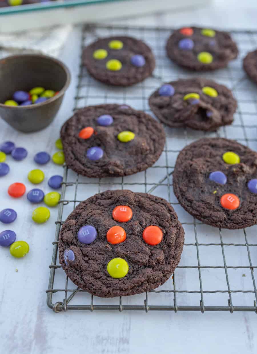 Dark chocolate Halloween M&M cookies on a cooling rack.