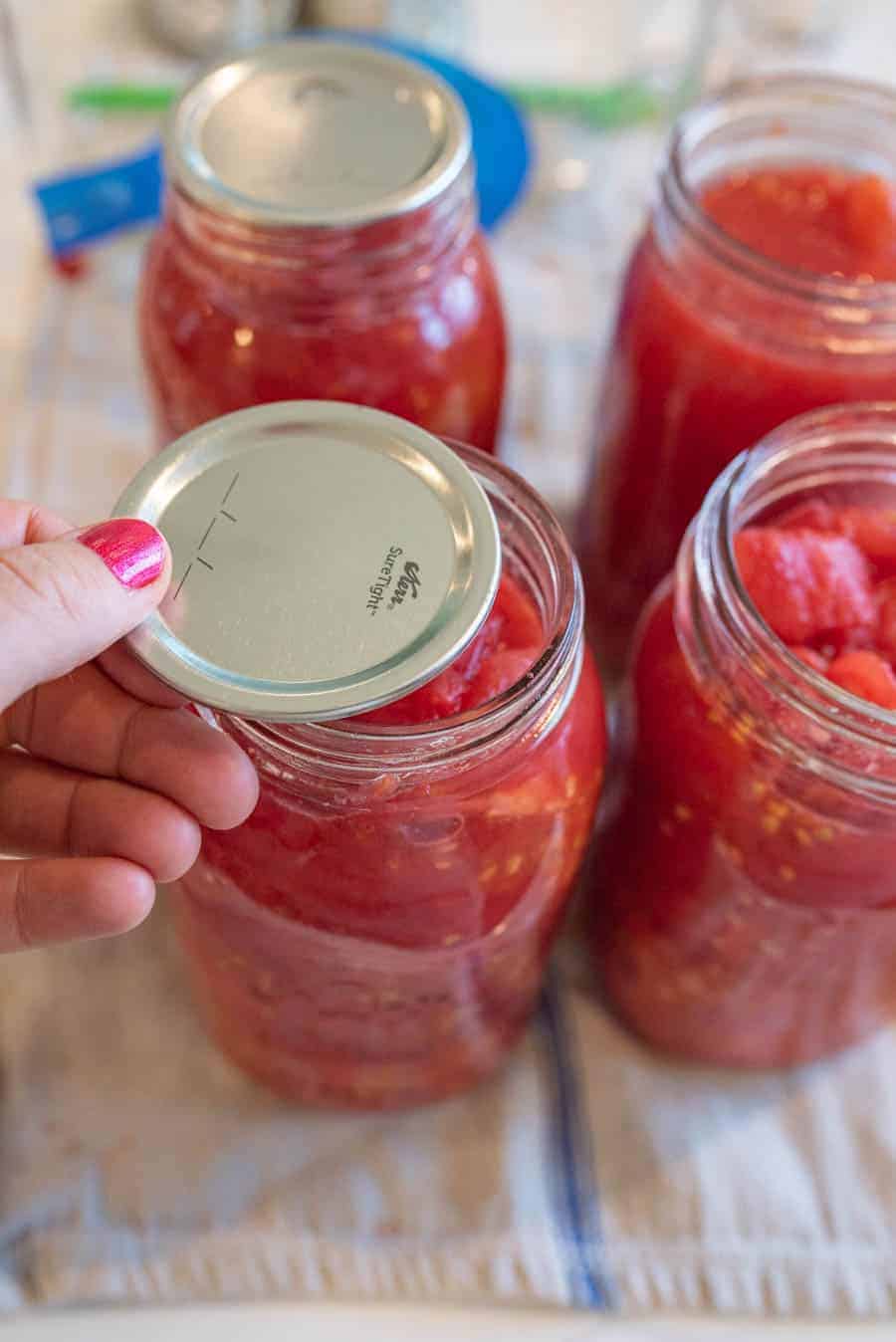 flat canning lid being added to jars.