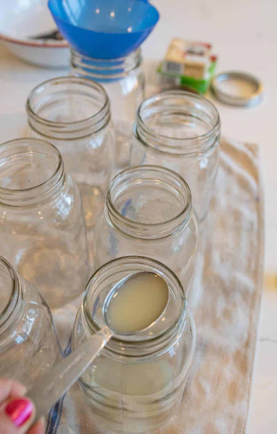 measuring spoon adding lemon juice to jars.
