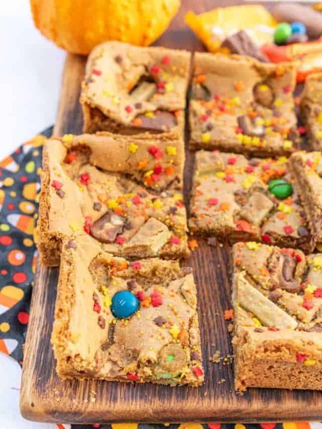 Halloween cookie bars with lots of assorted halloween candy on top cut into squares.