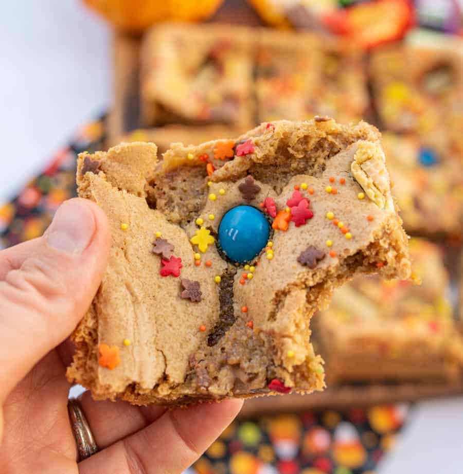 A Halloween cookie bar held in a hand with one bite taken.