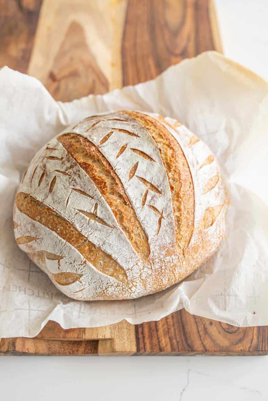 beautiful round loaf of rustic homemade bread that has been decorate and scored baked crispy and delicious.