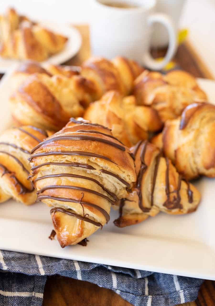 A close up of croissants on a plate drizzled with chocolate.
