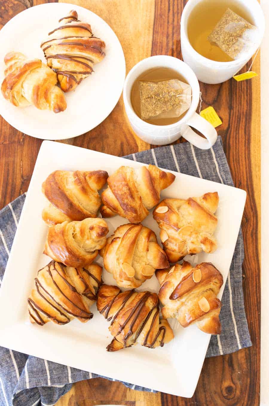 Top view of three kinds of croissants on a white plate with tea.