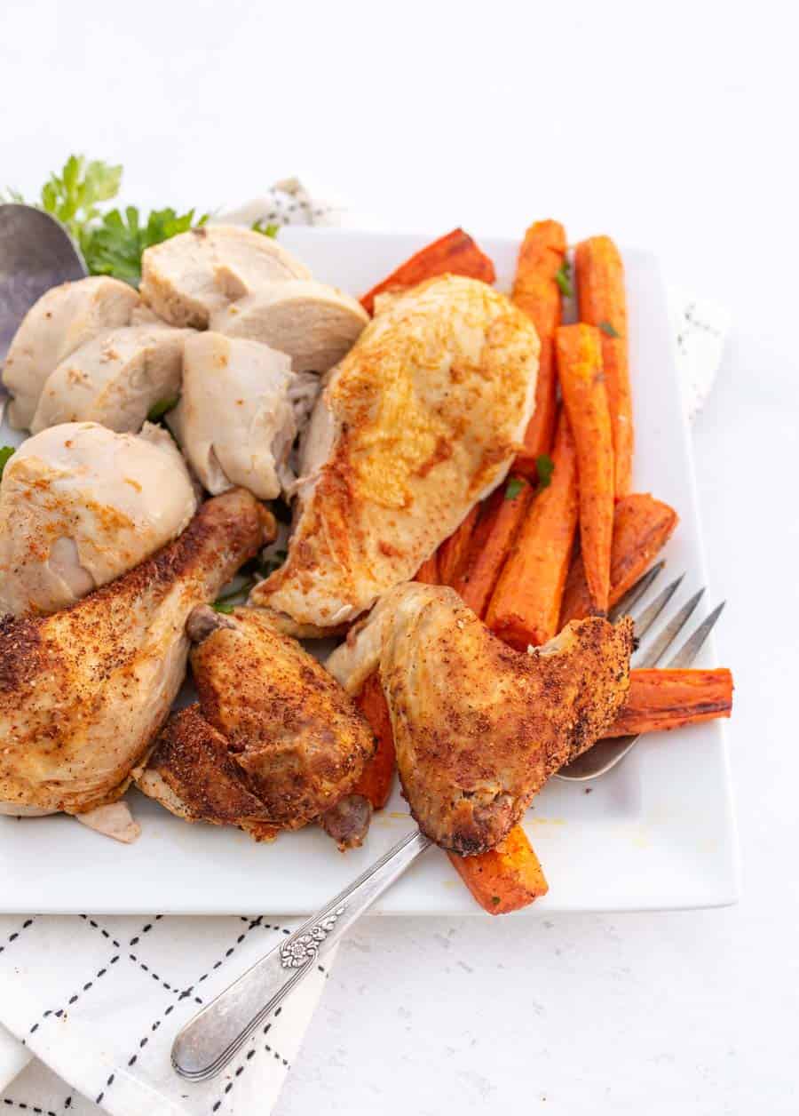 Roasted chicken cut in pieces on white plate with a fork.