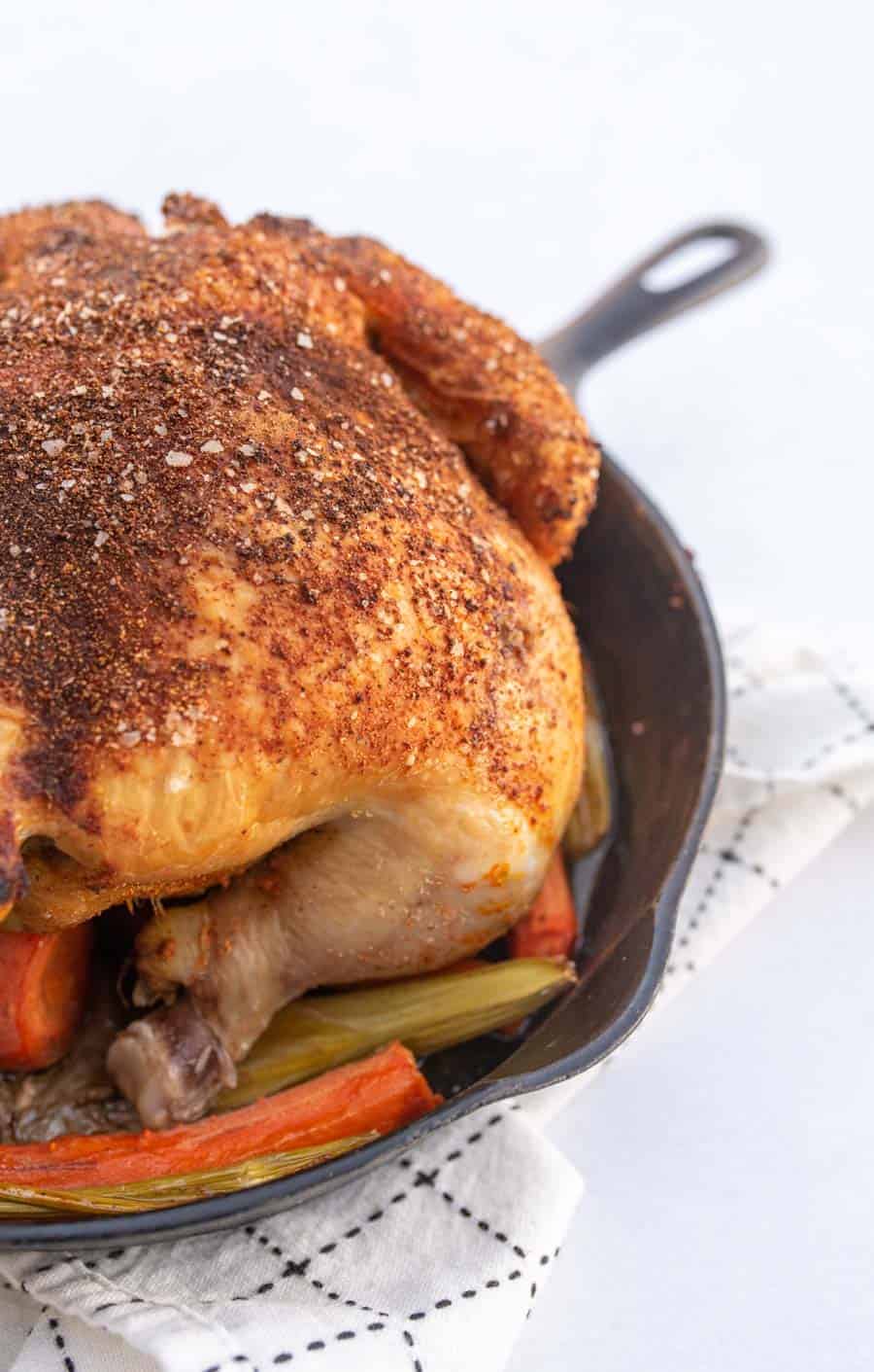 Close-up of a whole roasted chicken in a cast iron skillet.