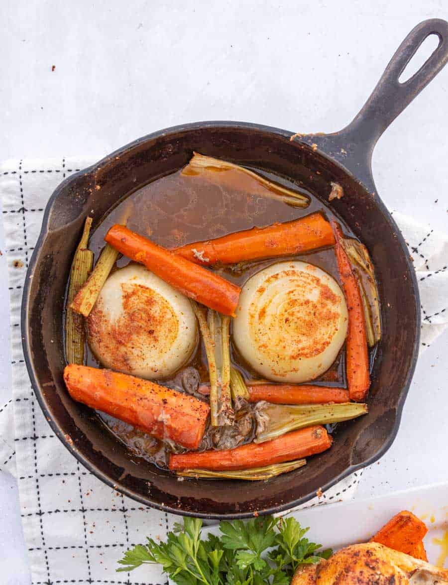 The carrots, celery, and onions in the bottom of the cast iron pan after the chicken was roasted.