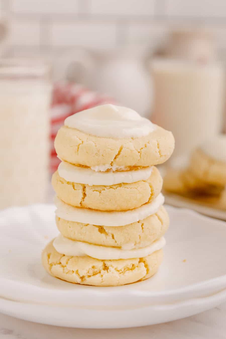 A stack of four baked and iced melt away cookies on a white plate.