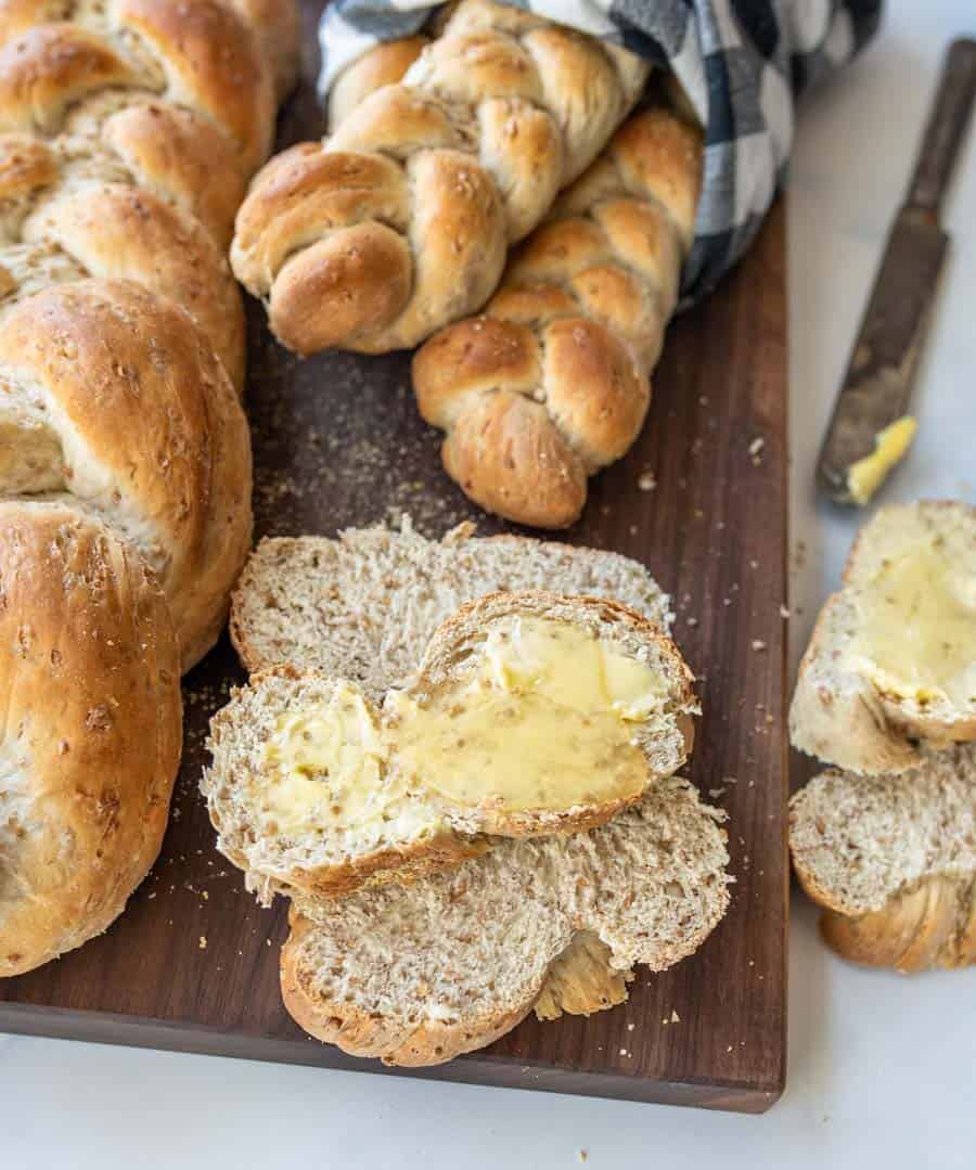 sliced bread with butter on a dark wood cutting board.