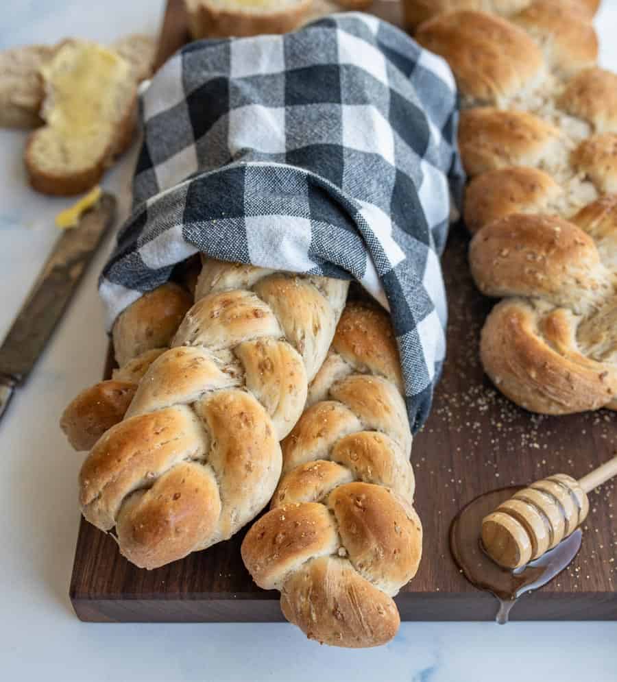 three small loaves of bread whole wheat bread wrapped in a black and white checked towel.