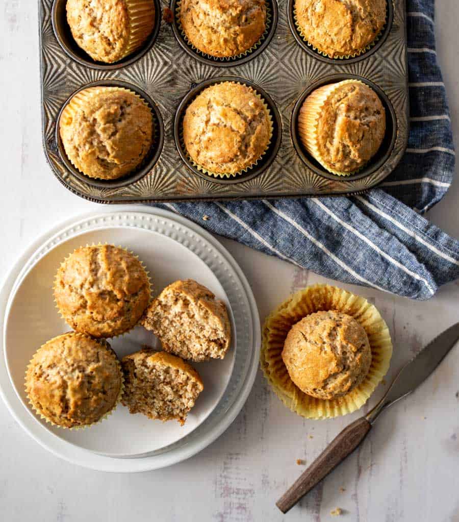 top view of fresh out of the oven bran muffins in tin and some on a plate split open.