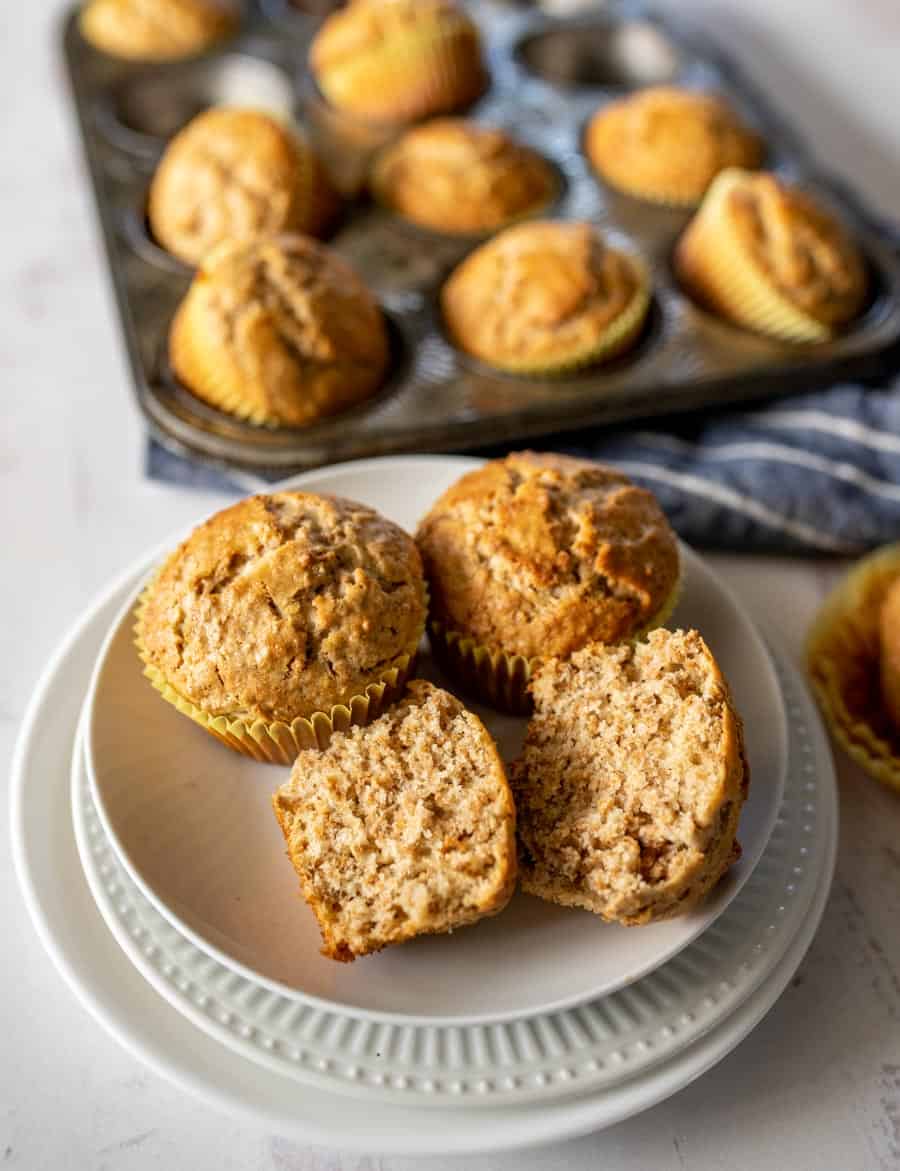 top view of fresh out of the oven bran muffins in tin and some on a plate split open.