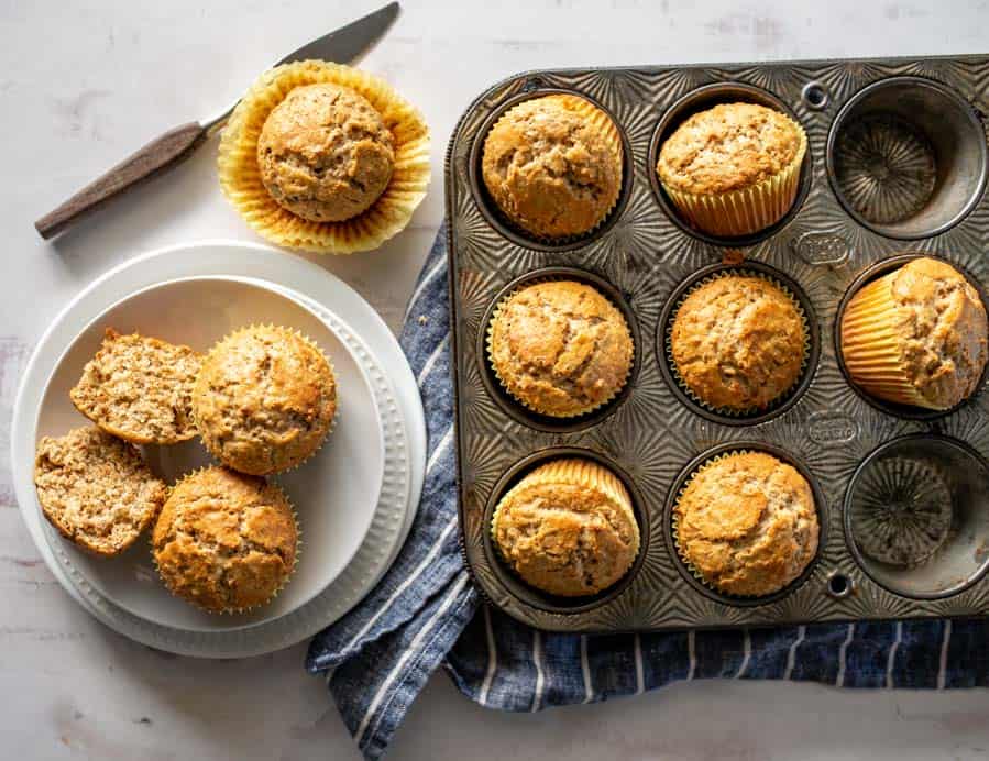 top view of fresh out of the oven bran muffins in tin and some on a plate split open.