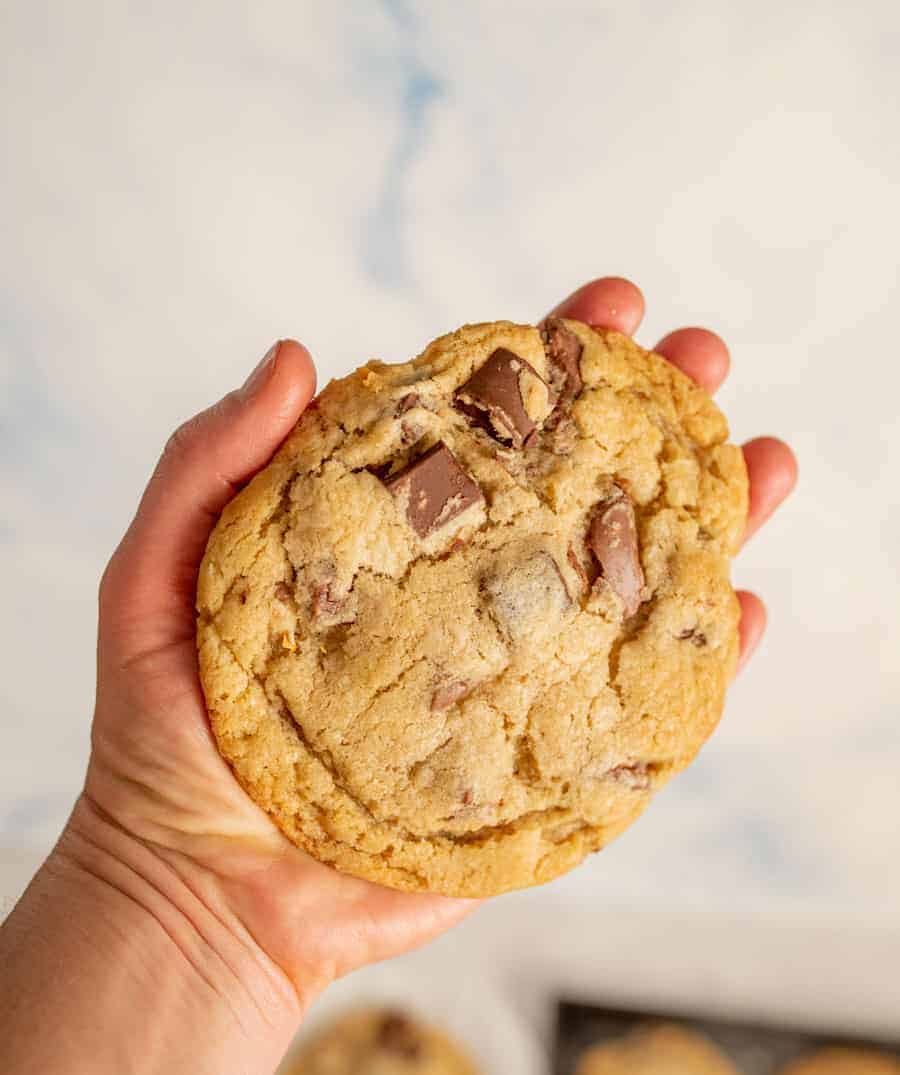 A giant chocolate chunk cookie in a hand.