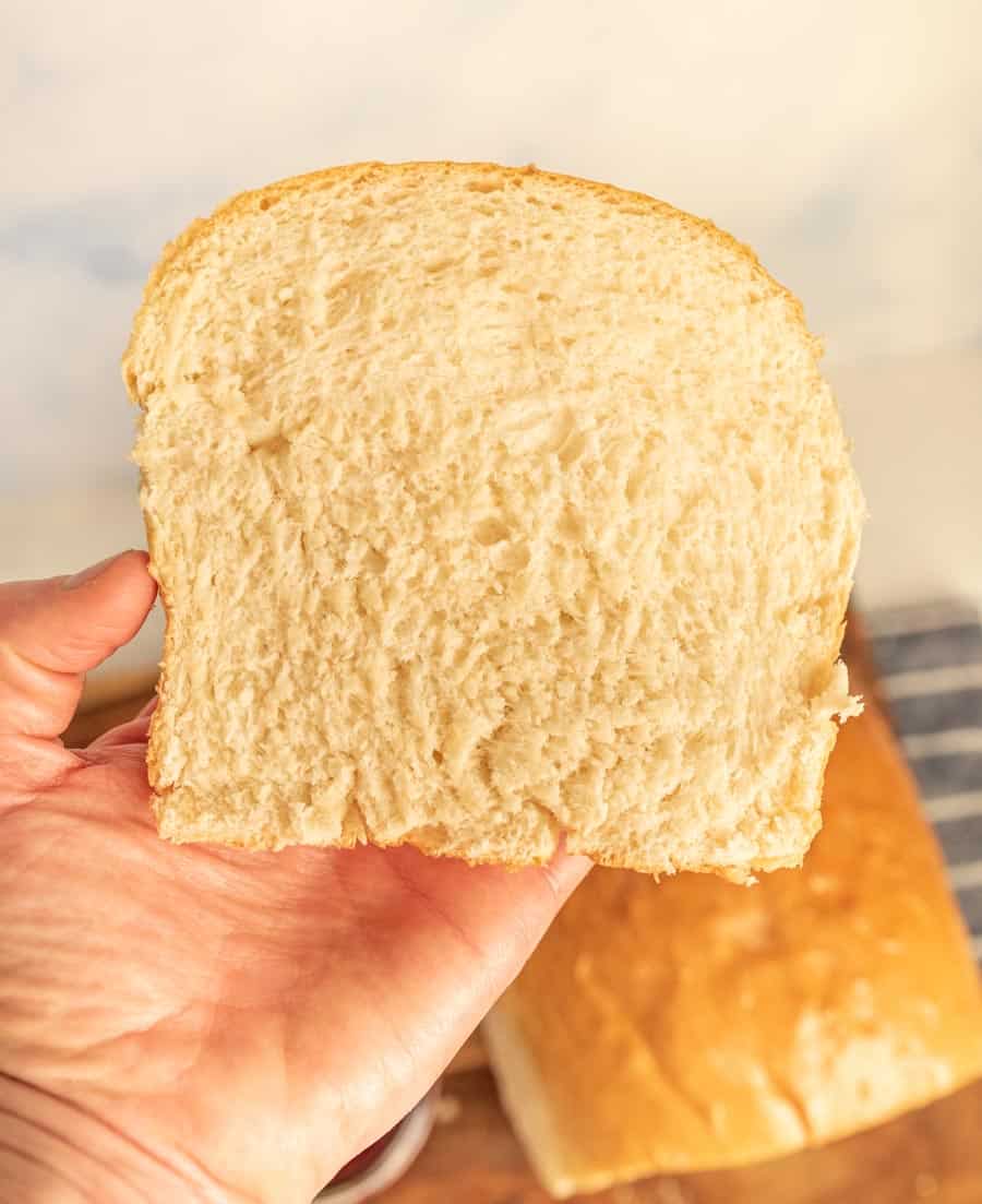 Hand holding a slice of white sandwich bread.
