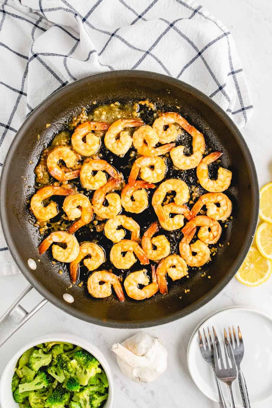 A pan of shrimp cooking in oil and garlic.