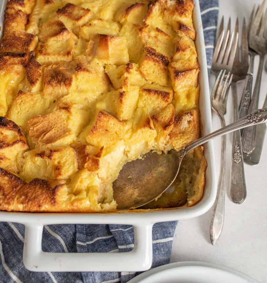 French toast breakfast casserole with a scoop missing out of the white baking dish with a spoon in it.
