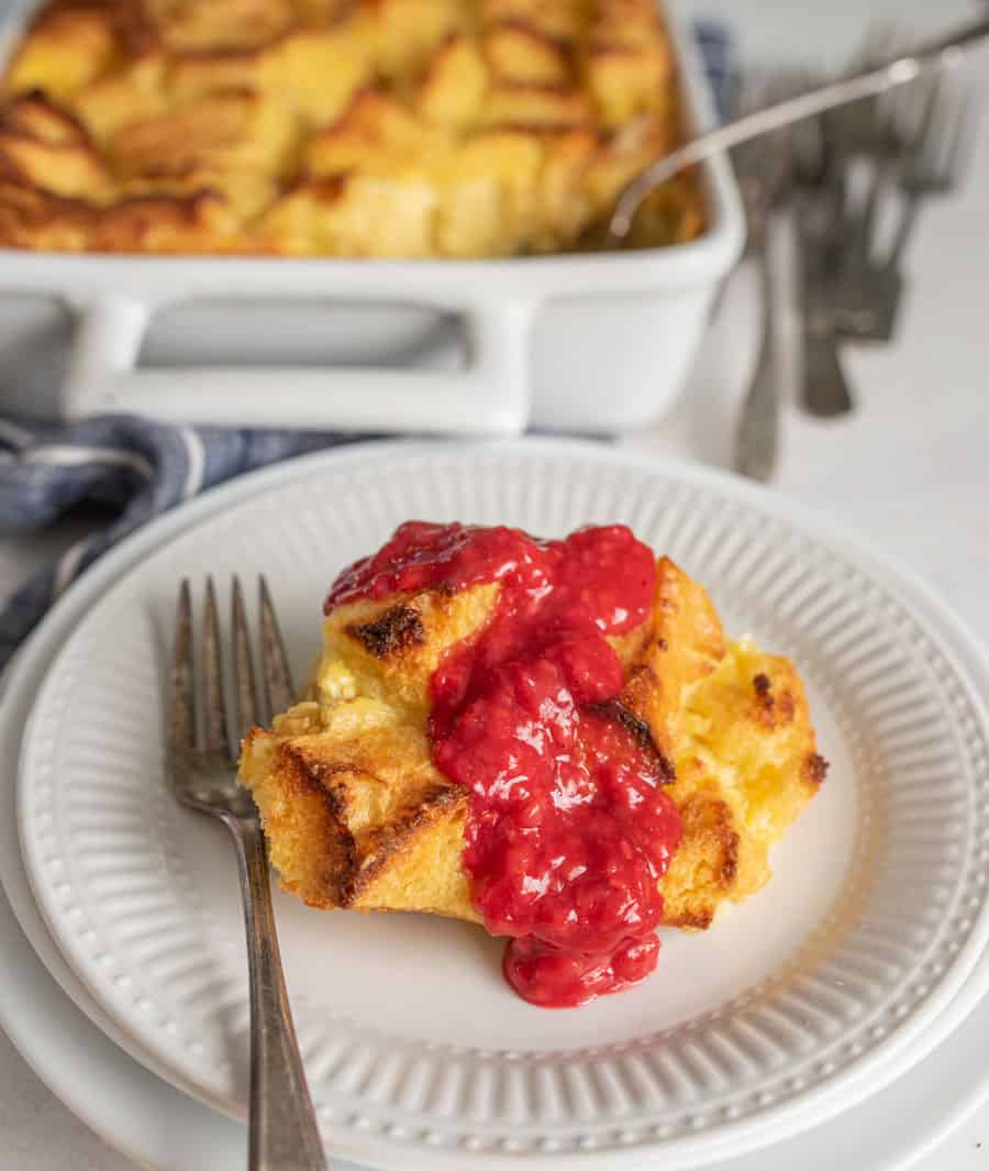 French toast breakfast casserole topped with raspberry sauce on white plate with a fork.