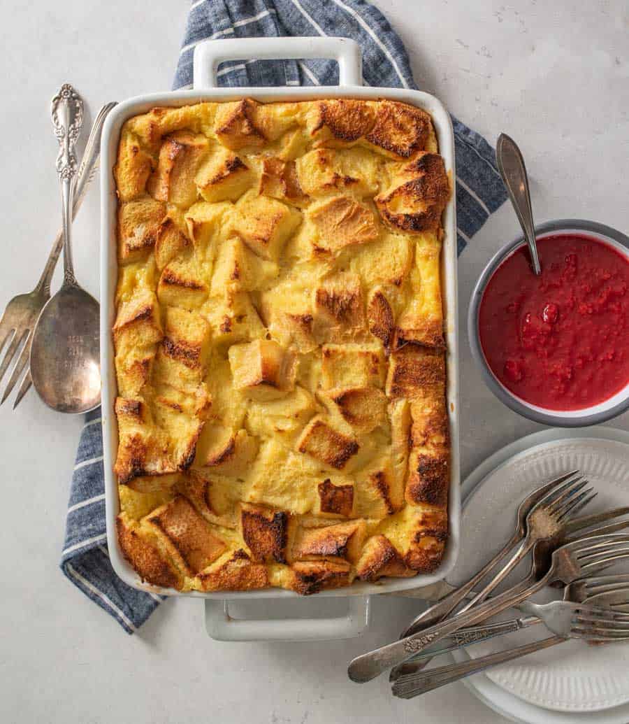 Top view of French toast breakfast casserole in a baking dish with plates and forks next to it.