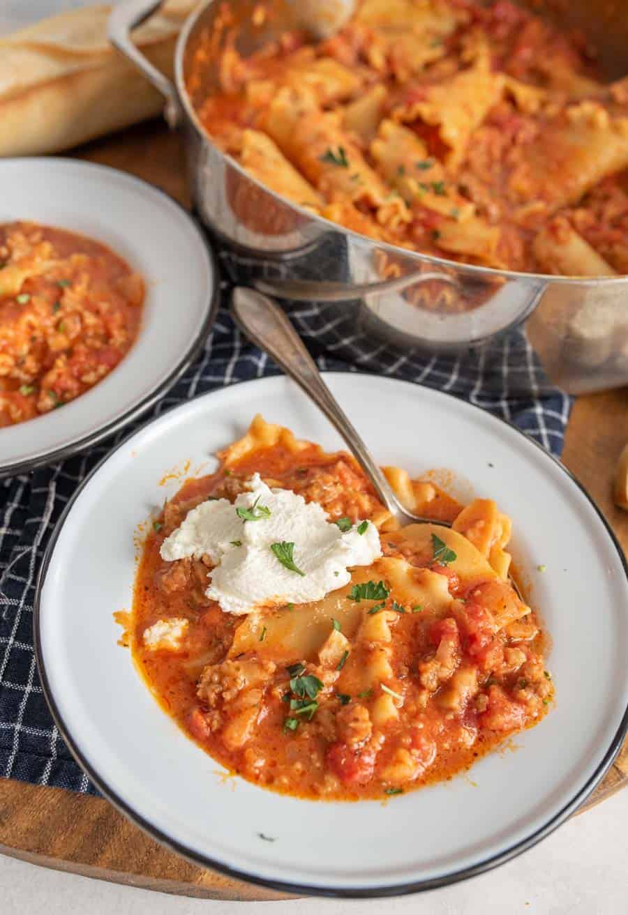 Bowled lasagna soup with a dollop of ricotta on top and parsley.