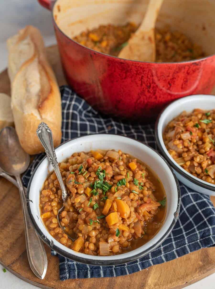 Vegetarian lentil soup topped with parsley in a white bowl with a spoon in it.