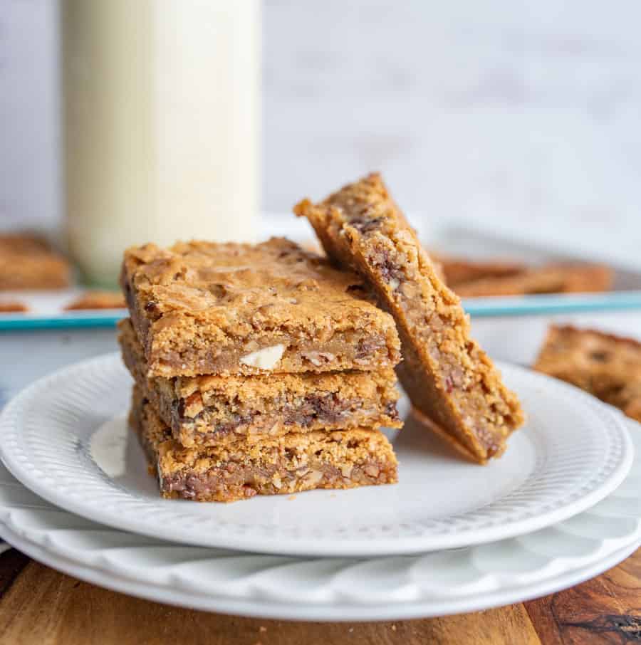 A close up of a white plate with blondies stacked on each other.