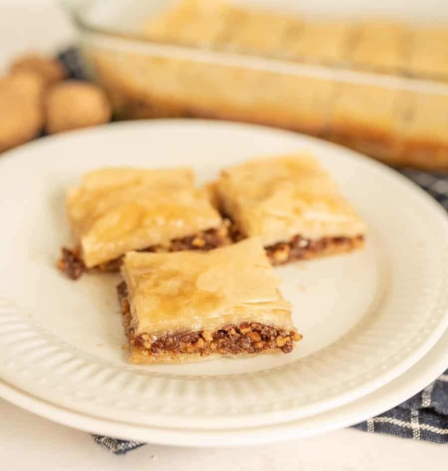 A close up of a plate of 3 squares of baklava.