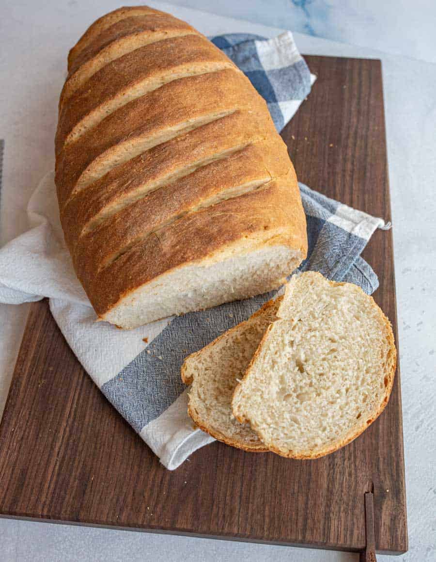 Top view of Italian bread on a wooden cutting board with a few slices cut off of it.