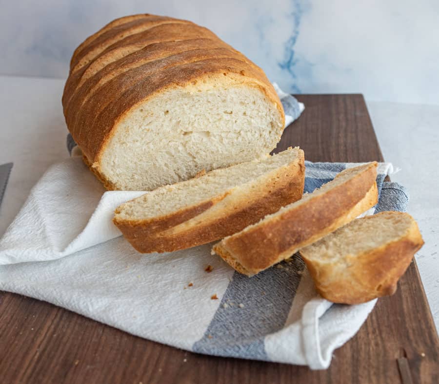 Italian bread with a few slices cut from it on a cutting board.