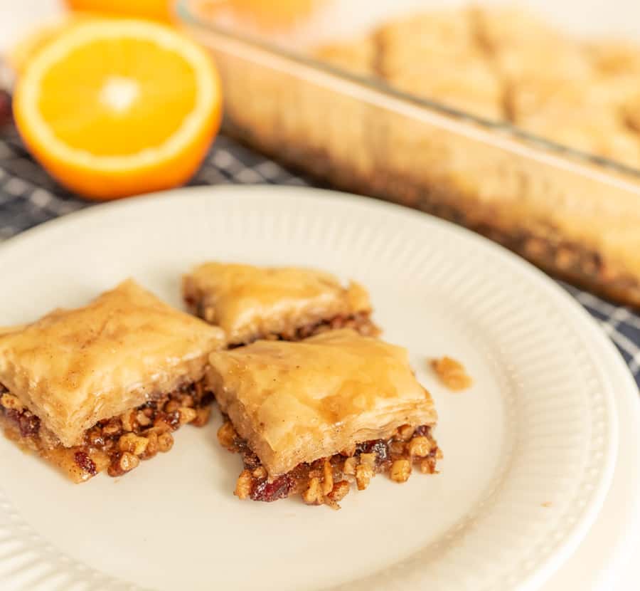 A close up of a plate with three slices of baklava on it.