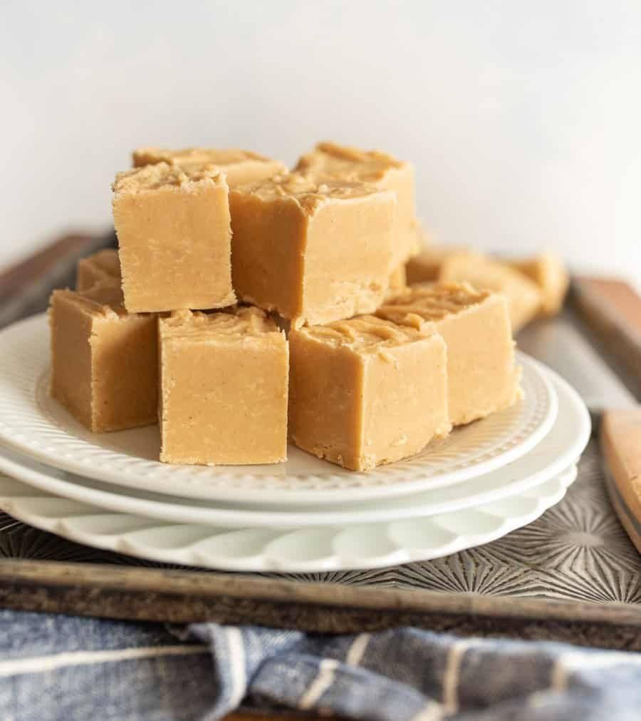 A close up of stacked peanut butter fudge squares on a white plate.