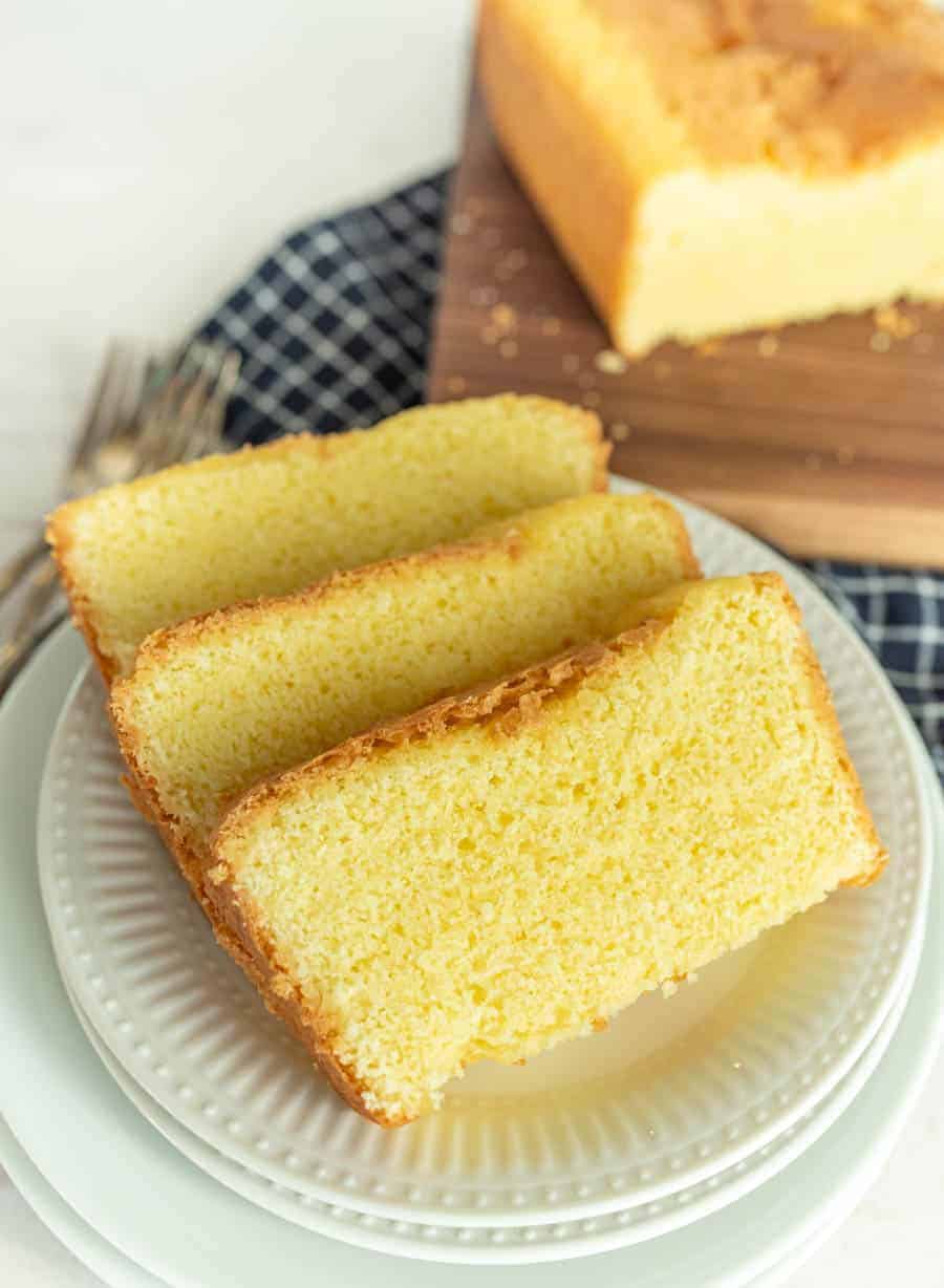Slices of pound cake on a plate with pound cake on a cutting board in the background.