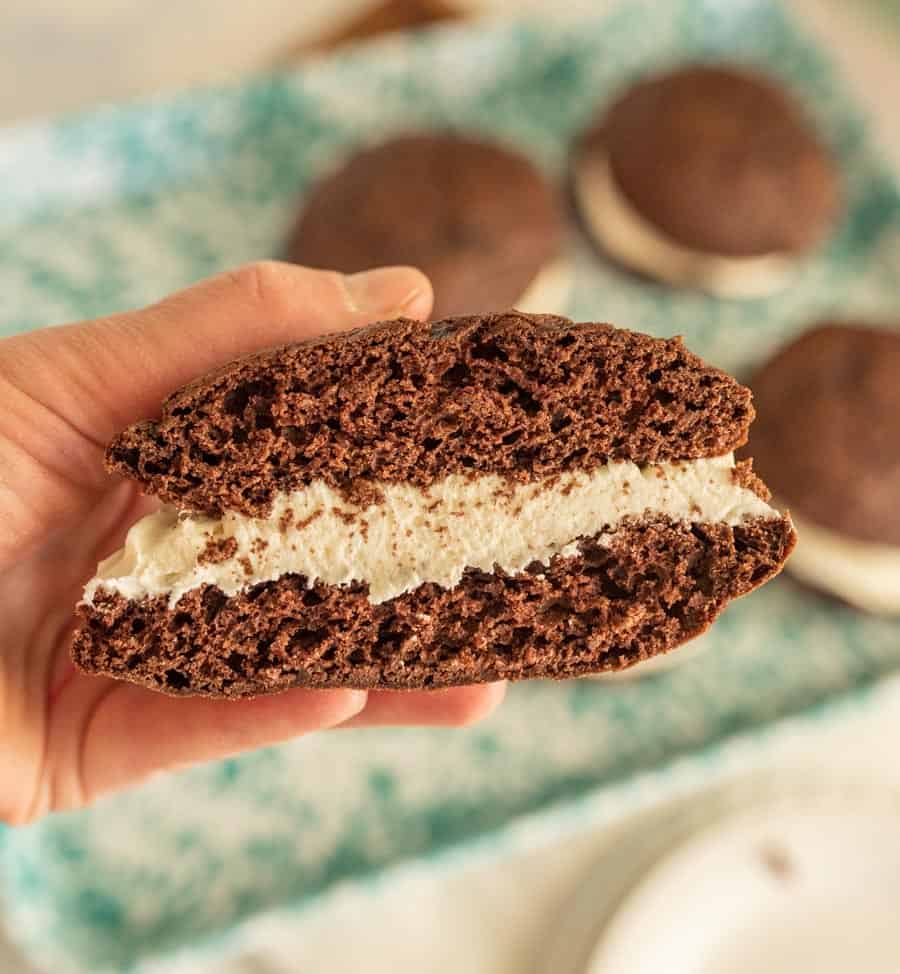A close up of a hand holding a whoopie pie cut in half.