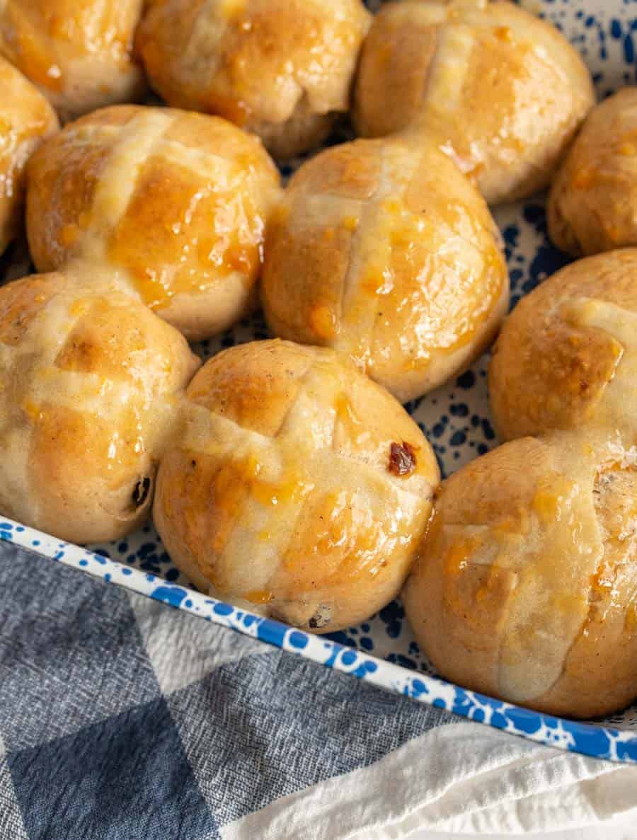 A close up of the glazed hot cross buns in a pan.