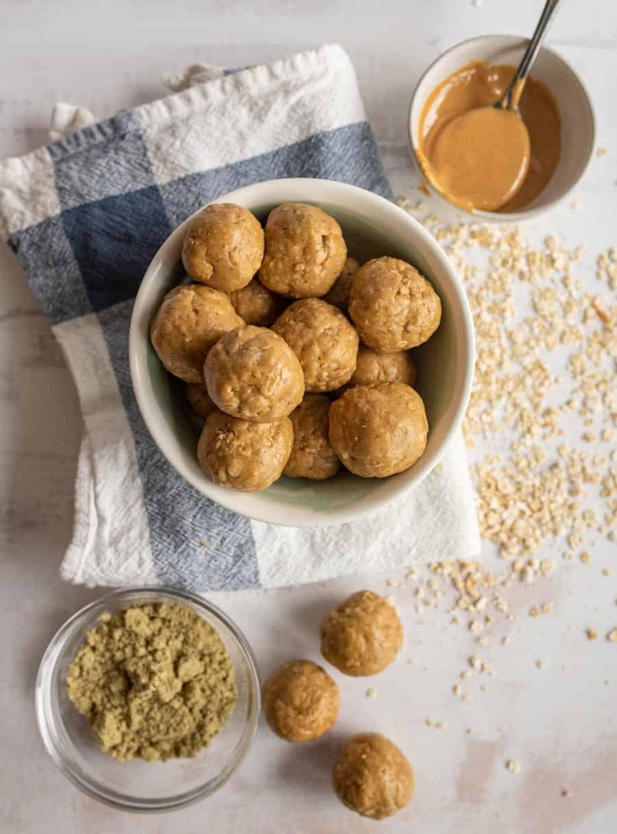top view of peanut butter protein balls in a bowl surrounded by the ingredients for the protein balls.