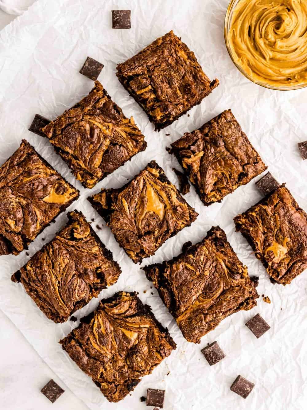 Top view of squares of peanut butter brownies with a bowl of peanut butter next to them.