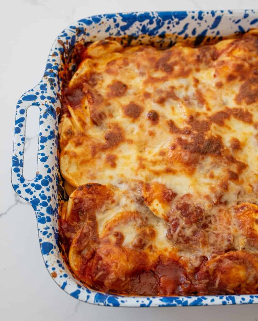 An up close shot of the baked ravioli lasagna in a blue speckled pan.