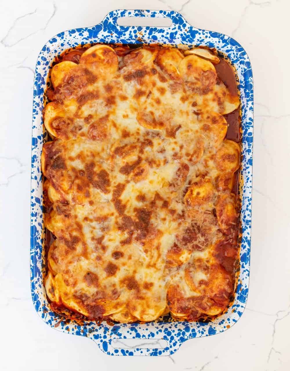 Top view of ravioli lasagna in a blue speckled baking dish.