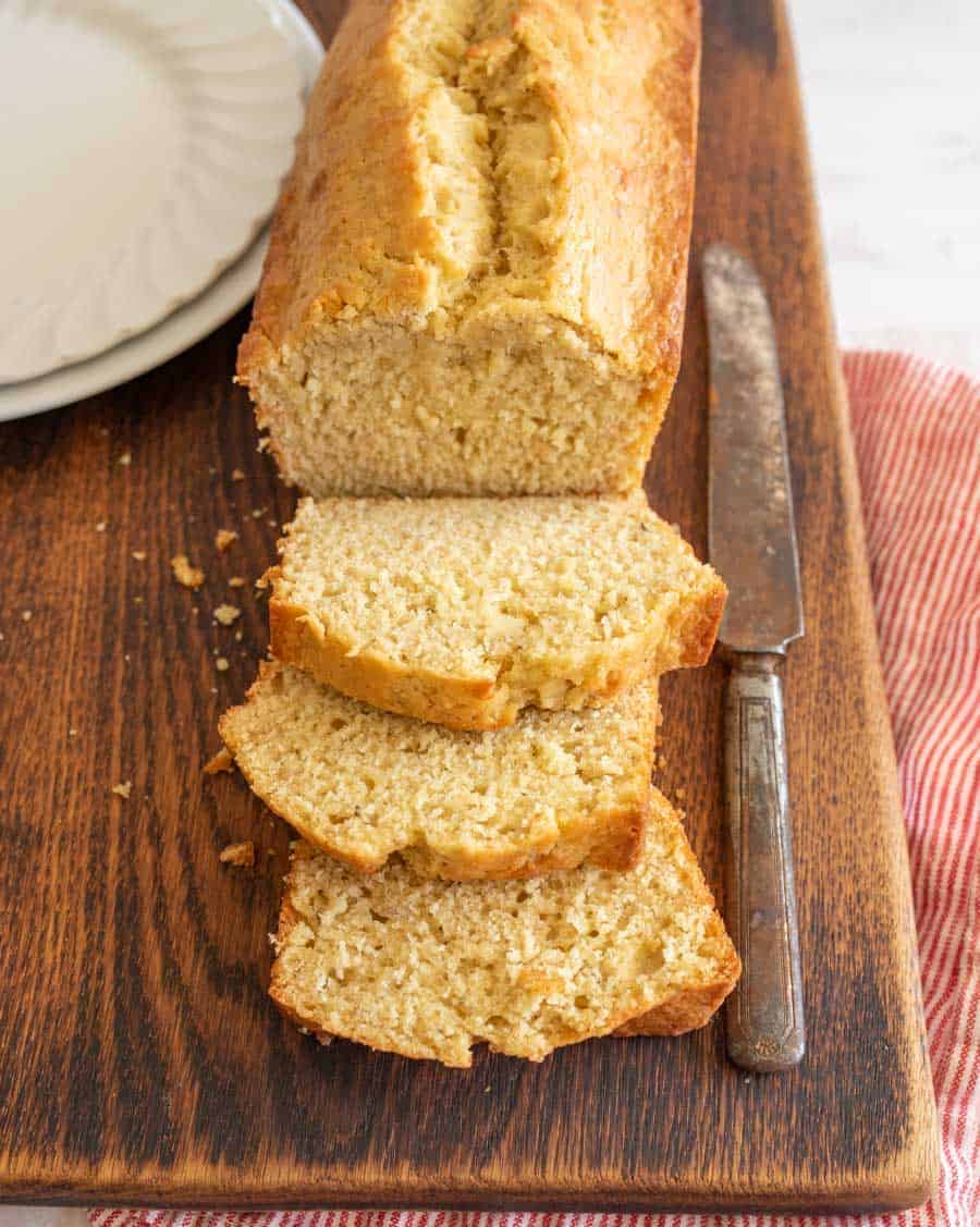 a cutting board with a loaf of banana bread that has several slices laying in front of it