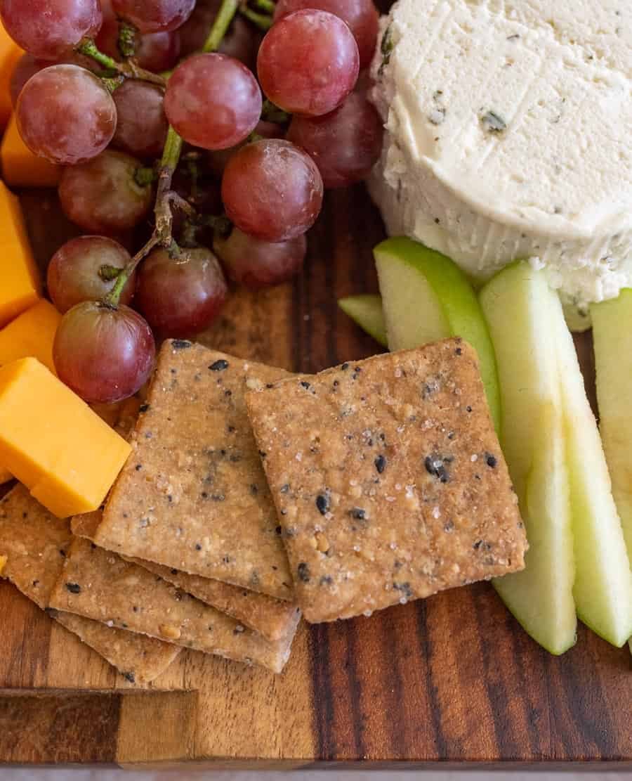 a close up photo of grapes, cheese, and crackers on a wooden board