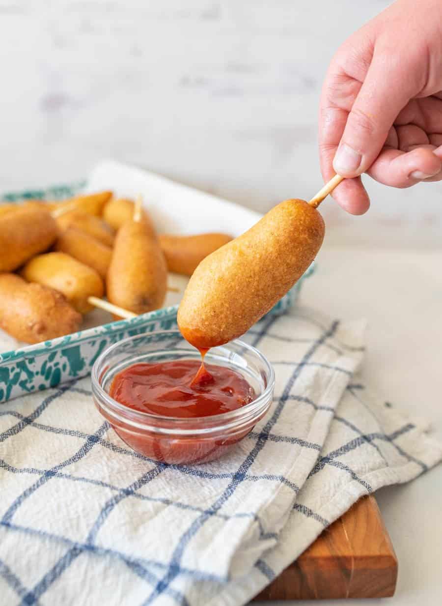 corndog being dipped into ketchup.