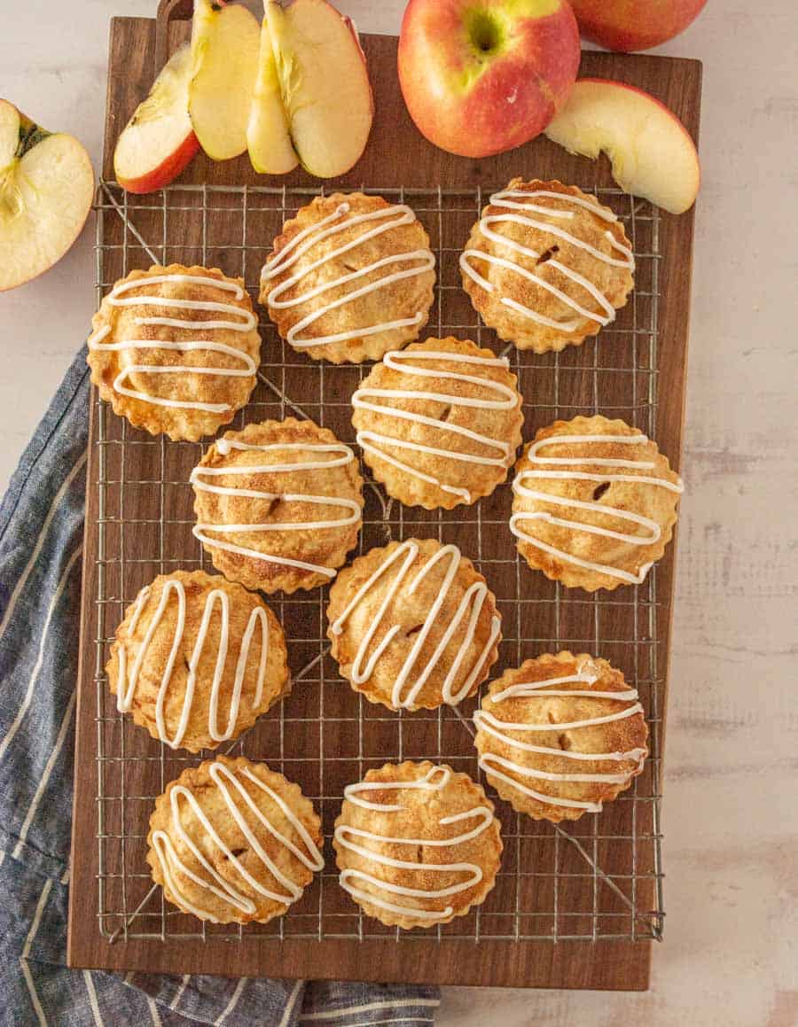 top view of apple hand pies on a cooling rack with apples on the side