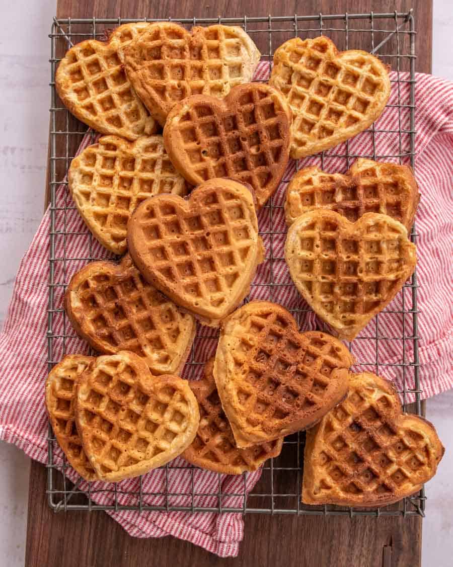 a plethora of heart-shaped banana pancakes on a cooling rack.