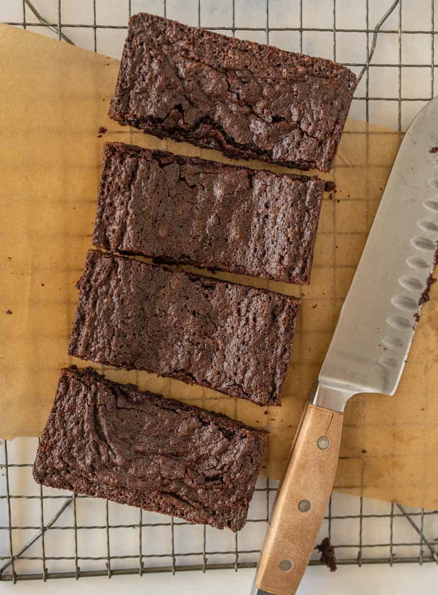 top view of brownies cut into bars next to a knife on a cooling rack
