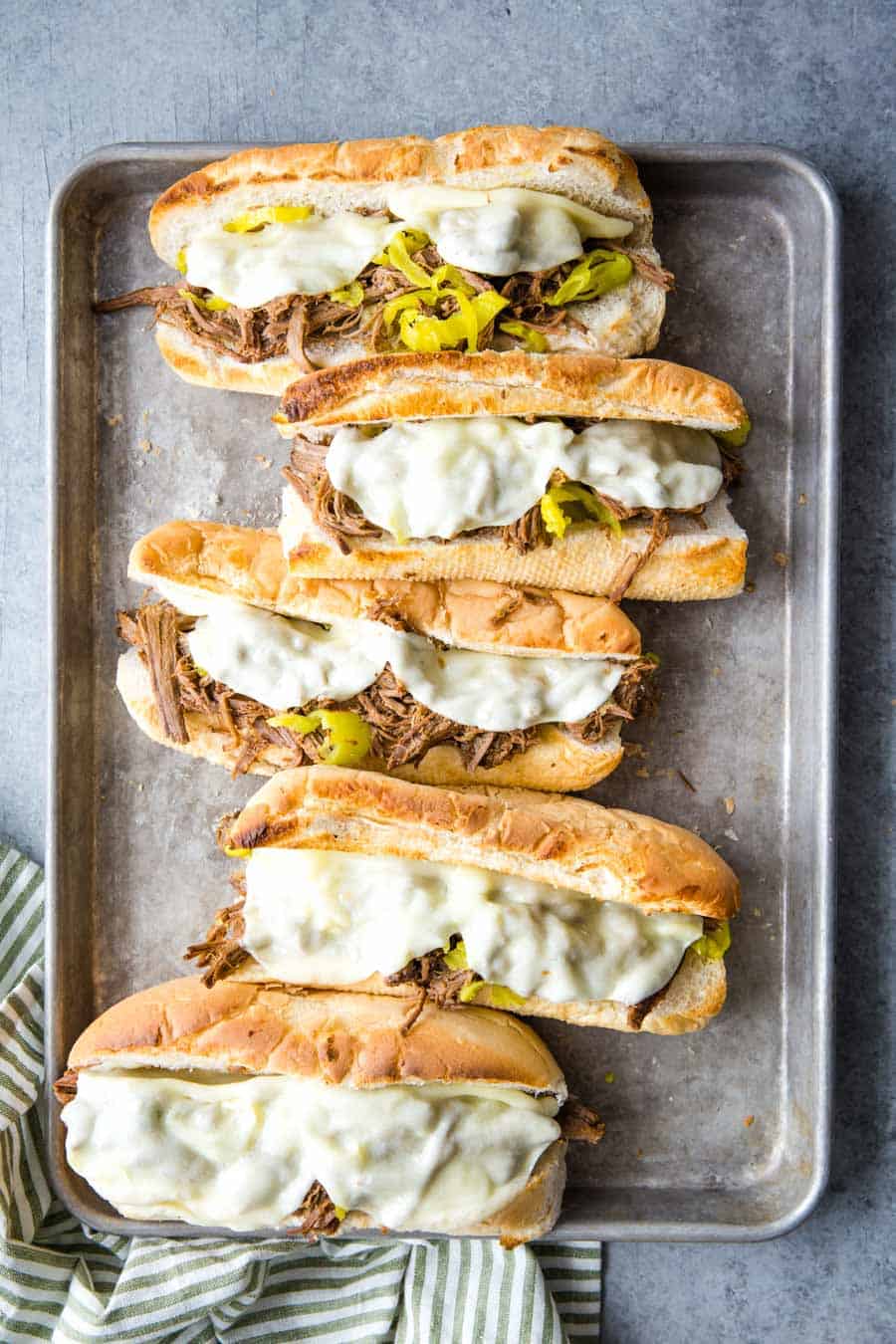 Overhead view of five Italian Beef Sandwiches on a baking sheet.