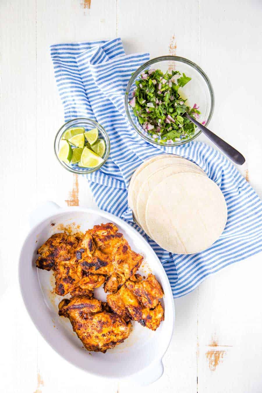 Top view of chicken, tortillas, and limes for chicken tacos.
