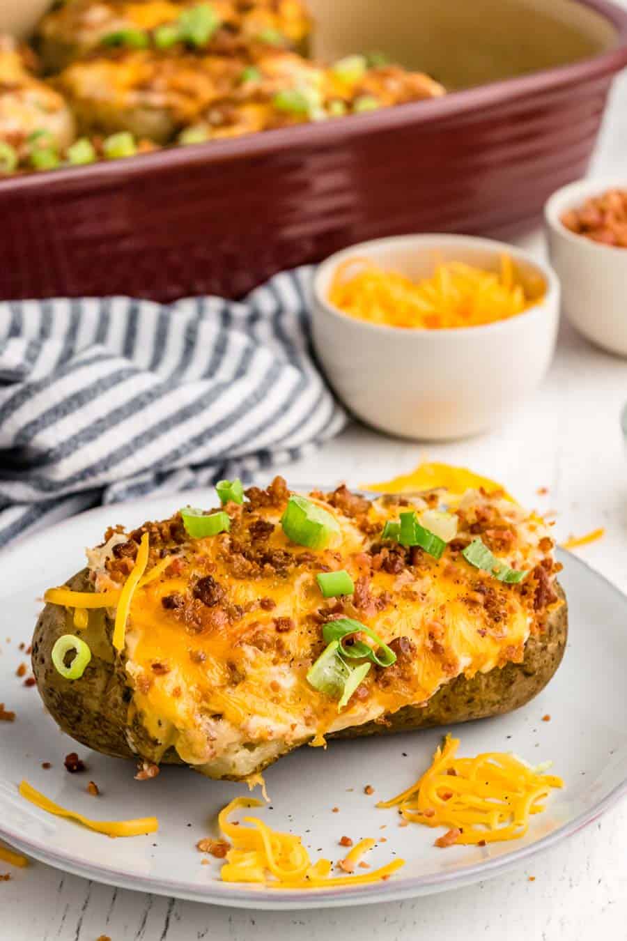 Side view of a twice baked potato on a white plate.