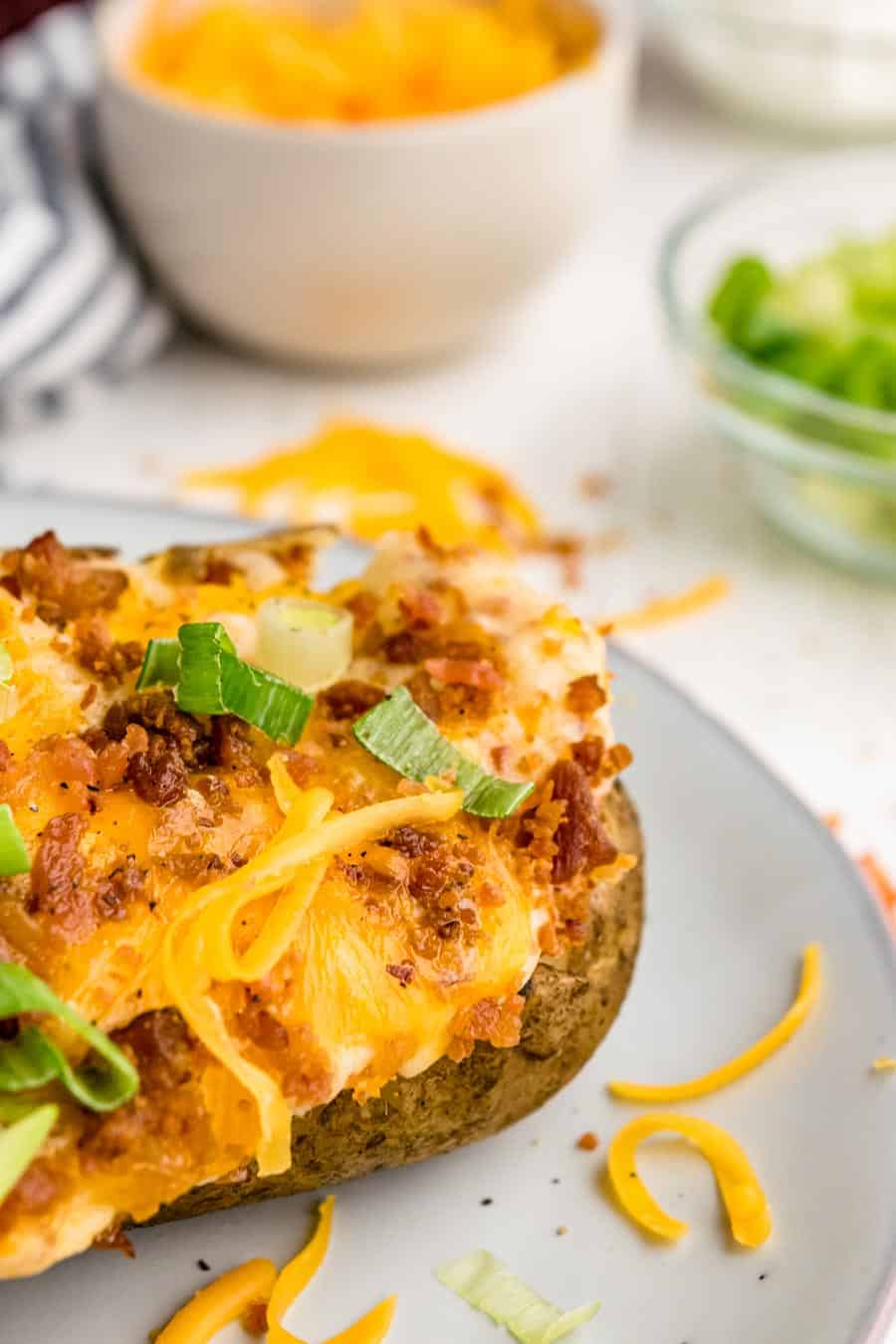 close up of twice baked potato on a white plate.