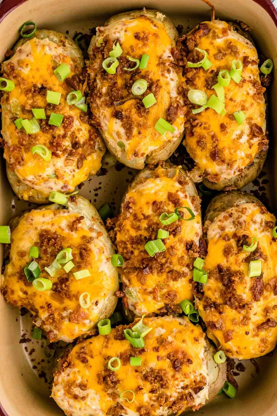 Top view of a whole pan of Twice Baked Potatoes topped with cheese, green onions, and bacon.