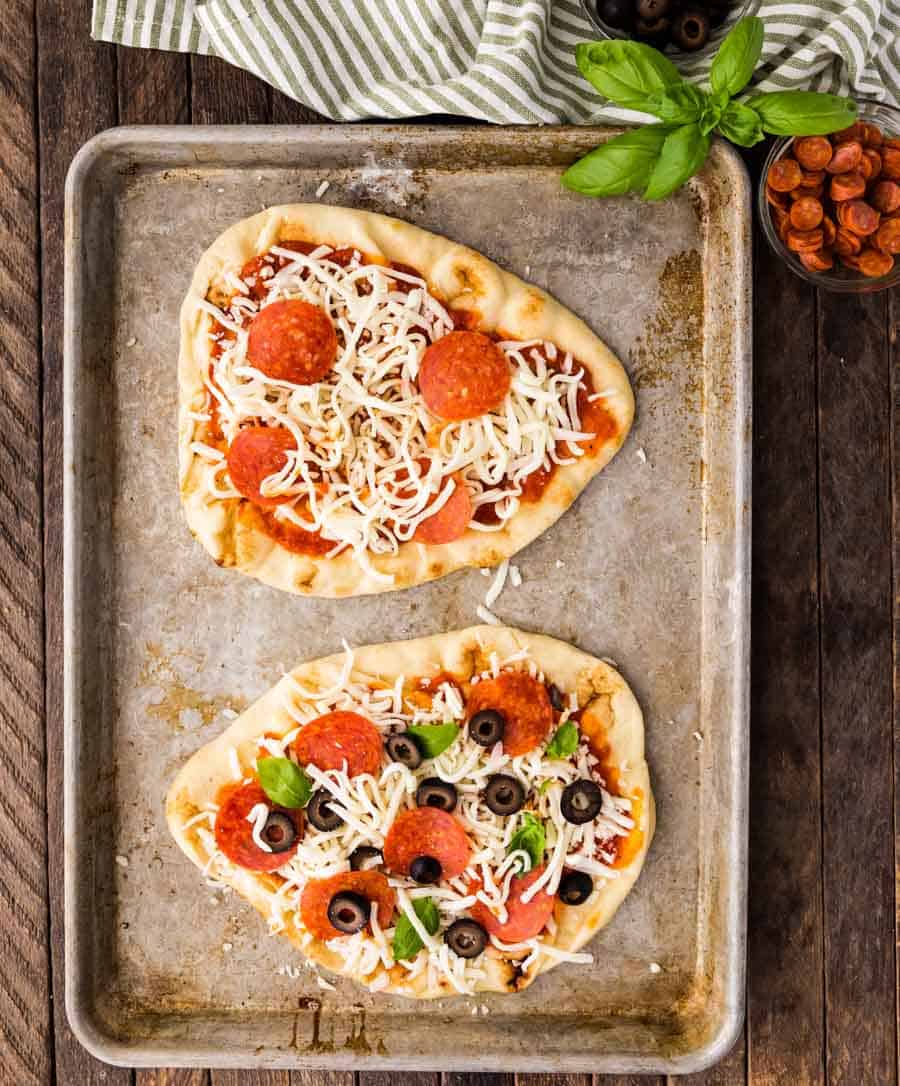 top view of unbaked flatbread pizzas on a baking sheet.